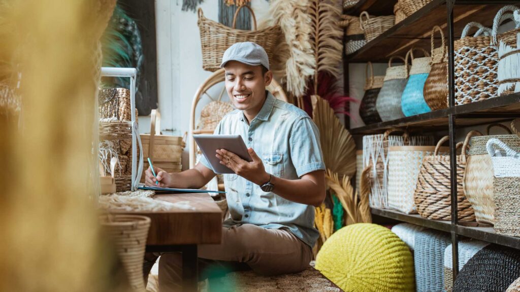 Young entrepreneur managing inventory with tablet inside a handmade goods shop.